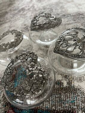 Four Ornate Glass Jars with Floral Silver-Tone Lids